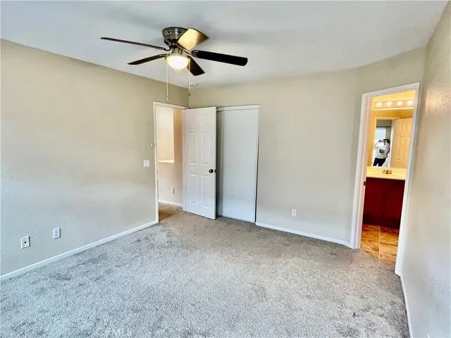 an empty room with closet and a chandelier fan