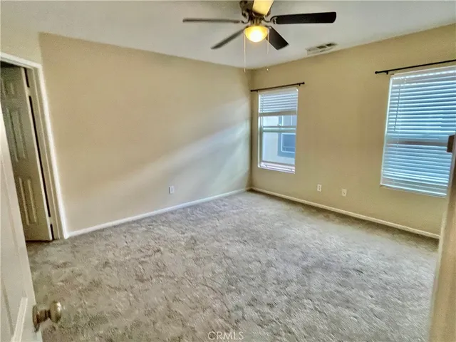 an empty room with a window and a fan