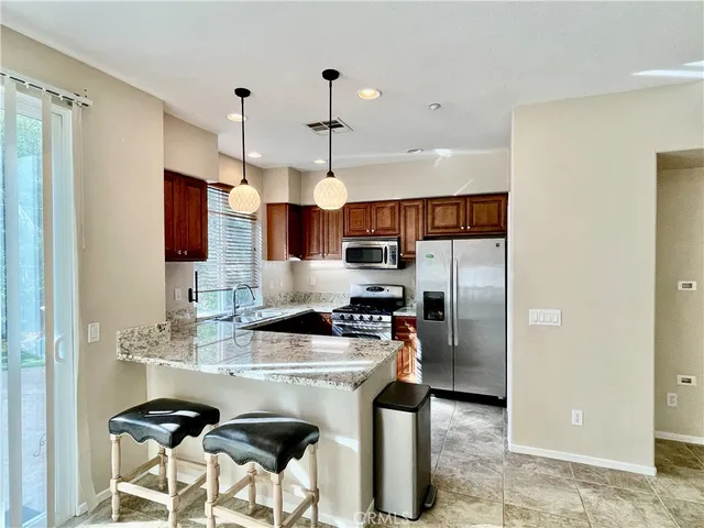 a kitchen with stainless steel appliances granite countertop a sink a stove a refrigerator and island