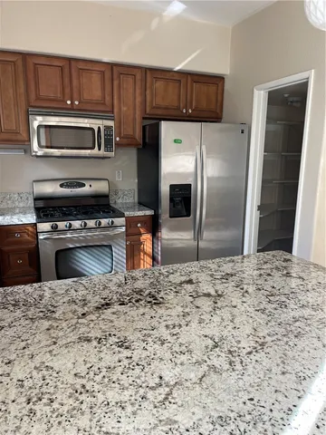 a kitchen with granite countertop a refrigerator stove and microwave