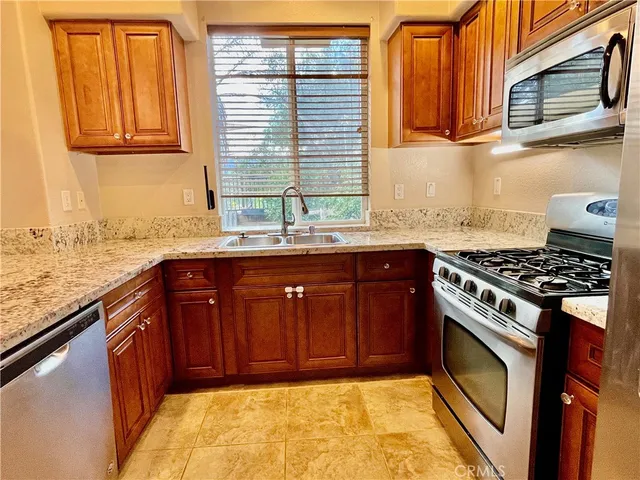 a kitchen with granite countertop stainless steel appliances a stove sink and cabinets