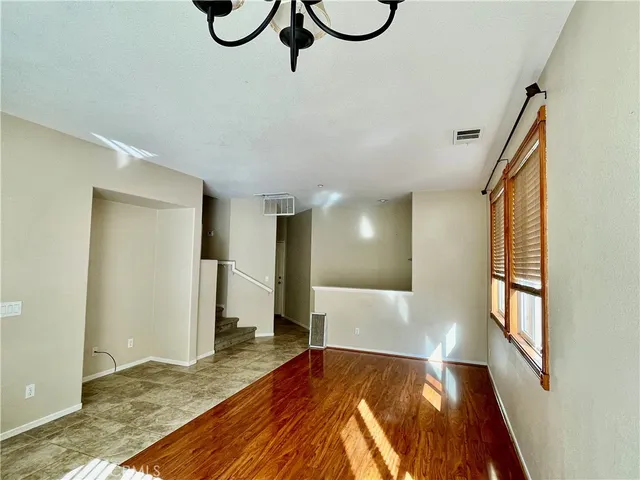 a view of an empty room with wooden floor and windows