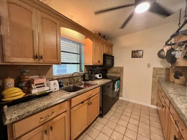 a kitchen with granite countertop a sink a stove and cabinets