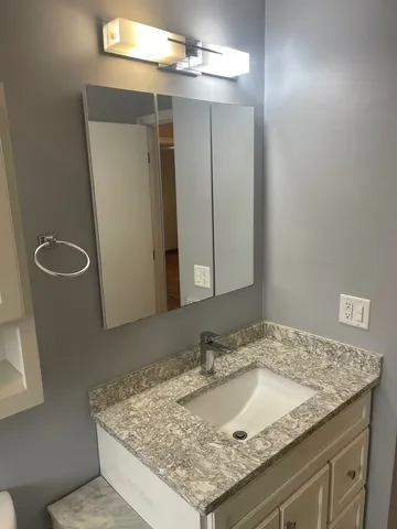 a bathroom with a granite countertop sink and a mirror
