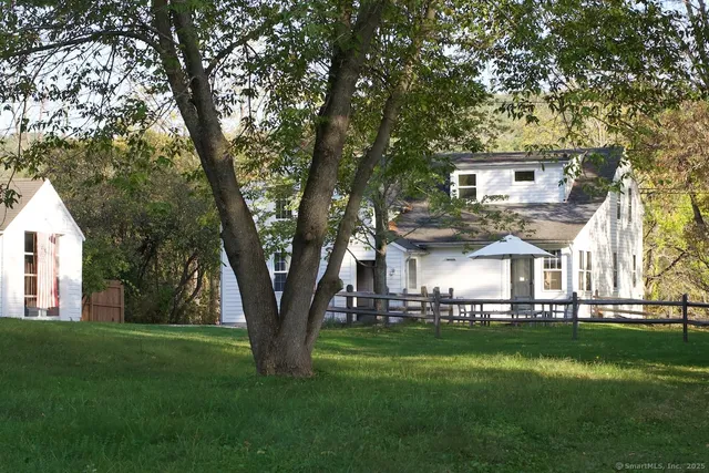 a view of a white house in a big yard with large trees