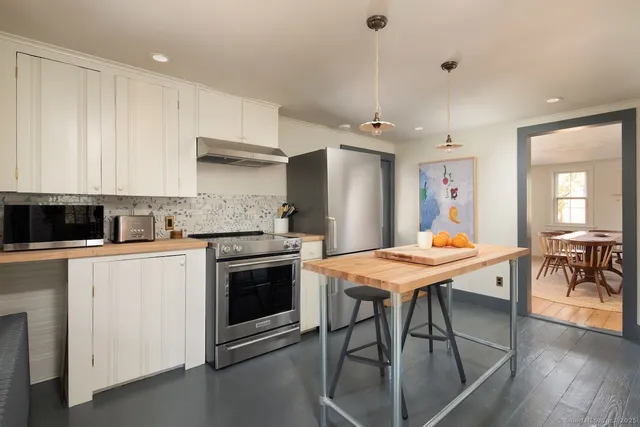 a kitchen with stainless steel appliances granite countertop a stove a refrigerator a kitchen island and chairs with wooden floor