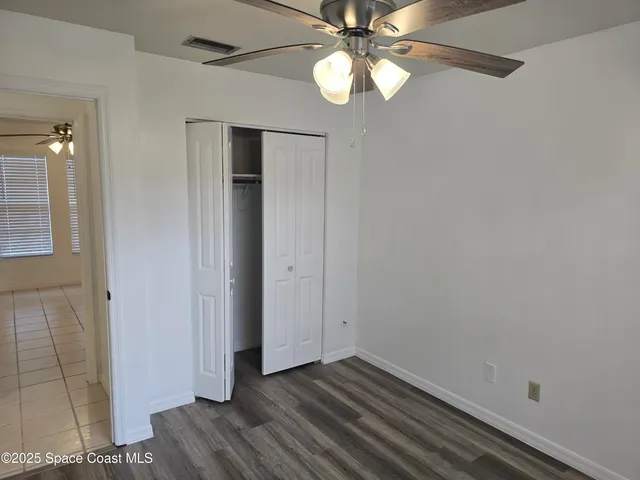 an empty room with wooden floor closet and windows
