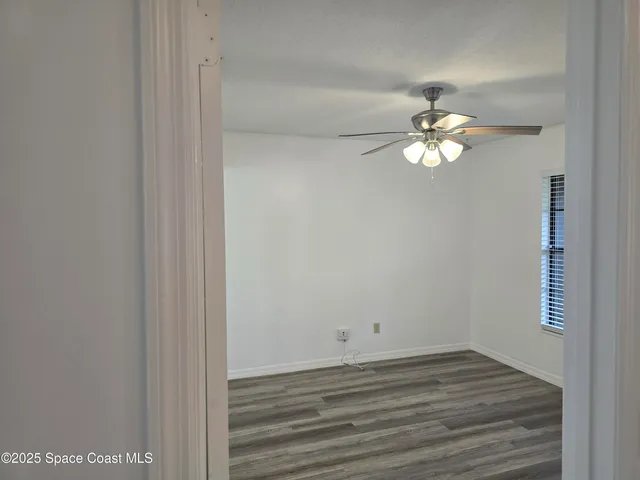 a view of empty room with wooden floor and ceiling fan