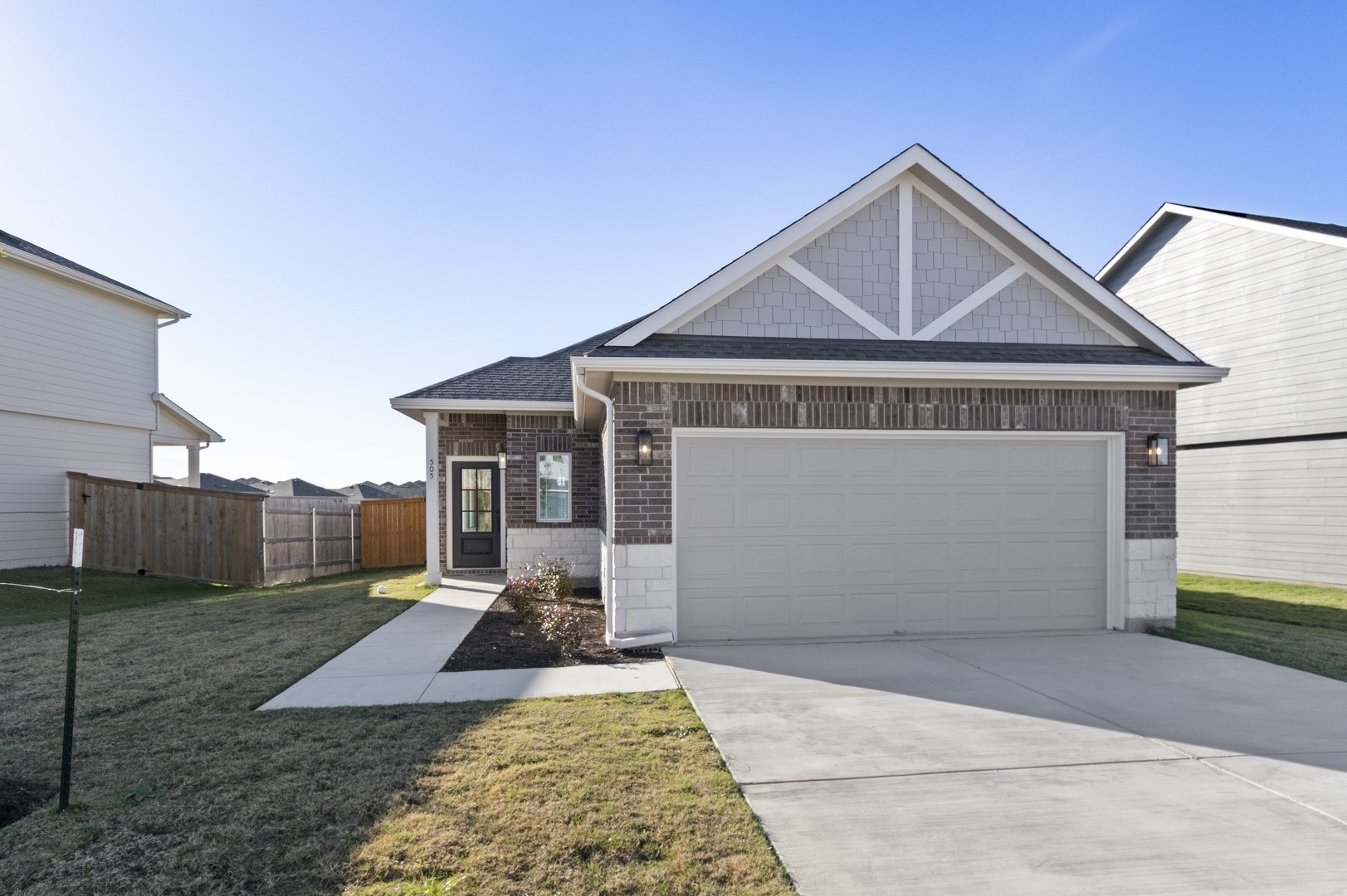 View of front of property with driveway, a shingled roof, brick siding, and a garage