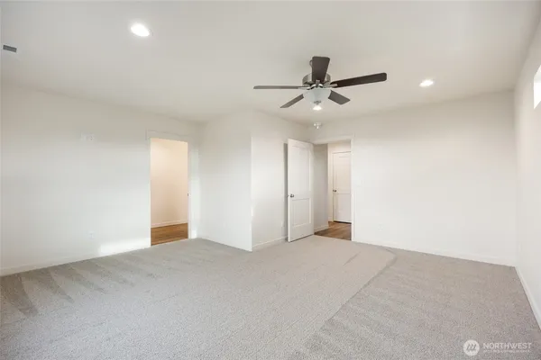 an empty room with a chandelier fan and windows