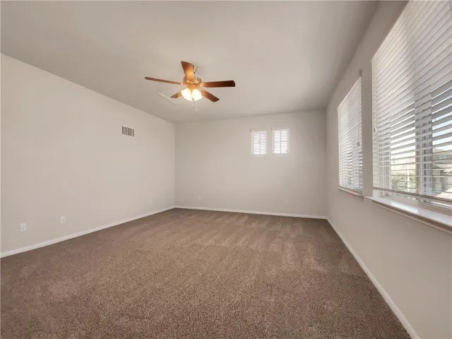 an empty room with windows and fan