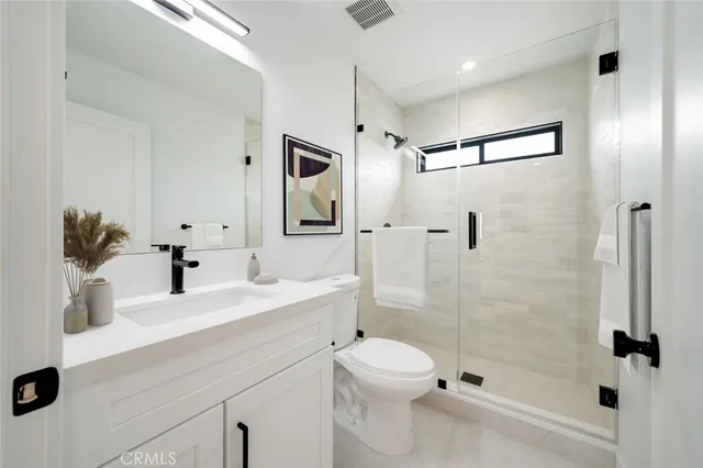 a bathroom with a shower sink vanity mirror and toilet