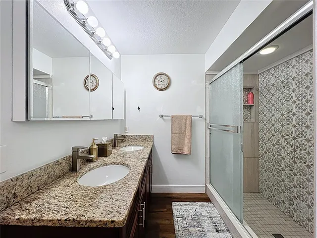 a bathroom with a granite countertop sink a mirror and shower