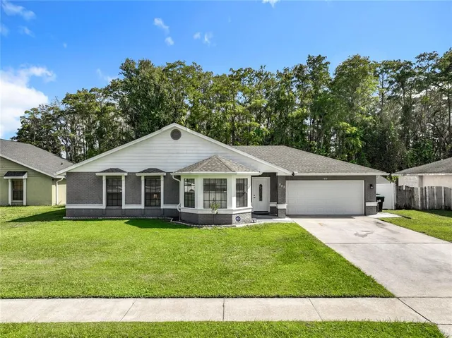 a front view of a house with a garden and trees