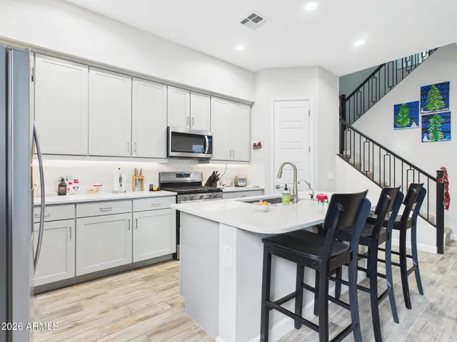 a kitchen with a sink chairs and white cabinets