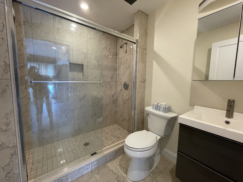 1028 Commonwealth Avenue, Unit 102 Boston, MA 02215 - Photo 10 of 11 a bathroom with a bathtub shower sink mirror and toilet