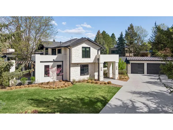 a view of a white house next to a yard with big trees