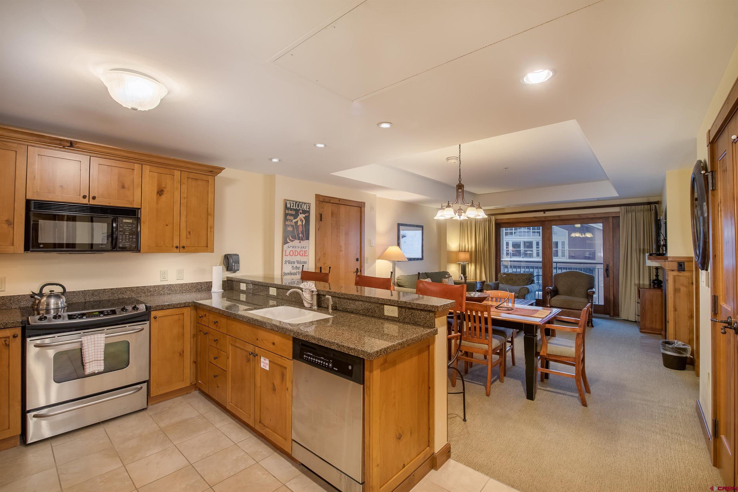 620 Gothic Road, Unit 504 Crested Butte, CO 81225 - Photo 4 of 33 a kitchen with a stove a sink a microwave and wooden cabinets