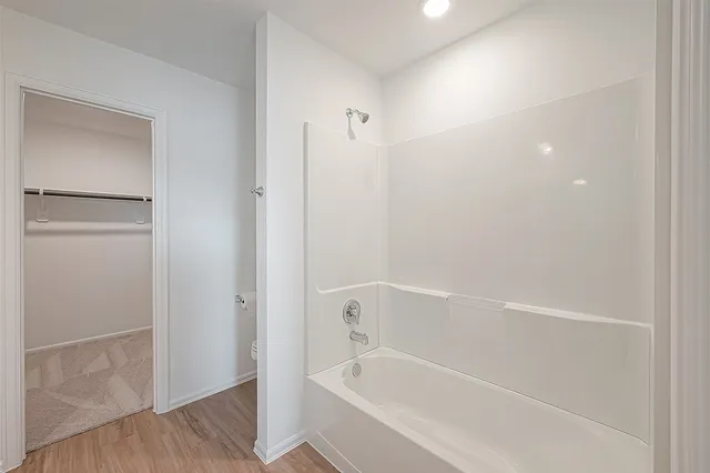 a white bath tub sitting next to a shower