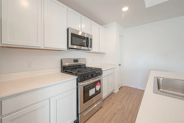 a kitchen with stainless steel appliances white cabinets and a stove top oven