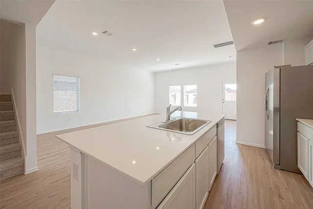 a kitchen with a sink a refrigerator and wooden floor