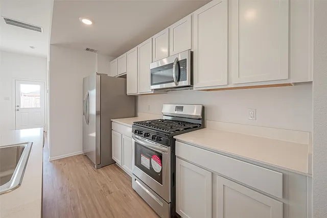 a kitchen with white cabinets and stainless steel appliances