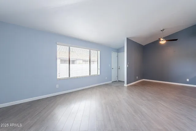 an empty room with wooden floor and windows