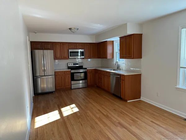 a kitchen with stainless steel appliances granite countertop a refrigerator a stove and a sink