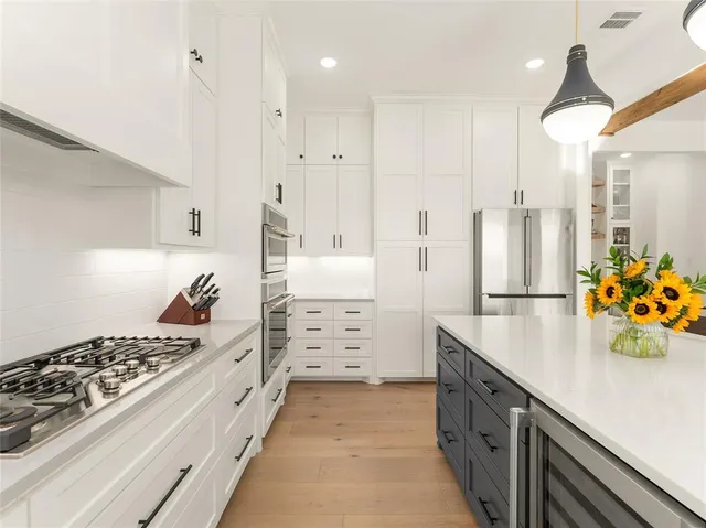 a kitchen with kitchen island white cabinets and stainless steel appliances