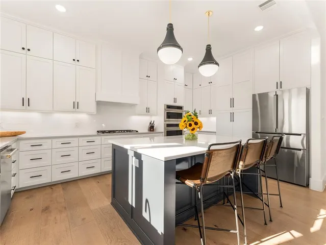 a kitchen with stainless steel appliances granite countertop a table chairs and a refrigerator
