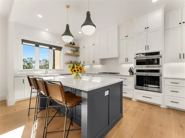 a kitchen with stainless steel appliances kitchen island granite countertop a table chairs in it and wooden floors