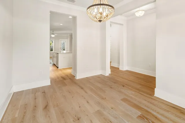 an empty room with wooden floor mirror and windows