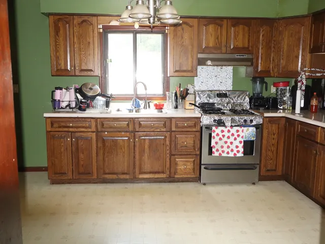 a kitchen with stainless steel appliances granite countertop a stove a sink dishwasher and cabinets with wooden floor