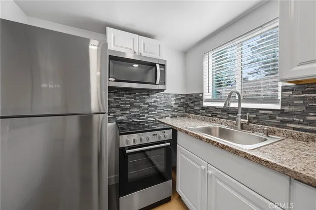 a kitchen with stainless steel appliances granite countertop a refrigerator sink and microwave