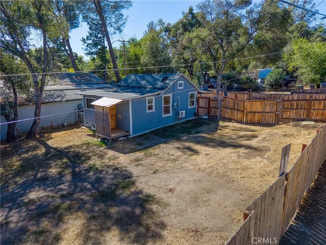 a backyard of a house with wooden fence and large trees