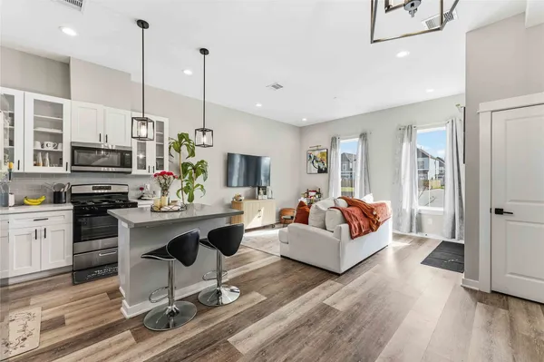 a living room with furniture a fireplace kitchen view and a flat screen tv