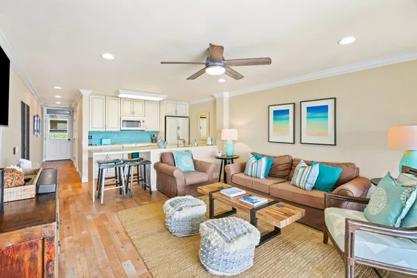 a living room with furniture kitchen view and a wooden floor