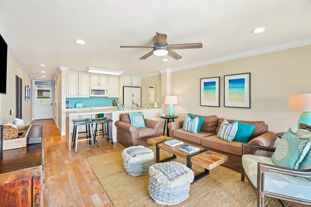 a living room with furniture kitchen view and a wooden floor
