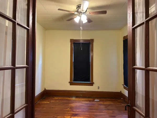 a view of an empty room with wooden floor and a window