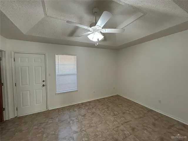 an empty room with a chandelier fan and windows