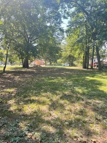 a big yard with lots of green space and trees all around
