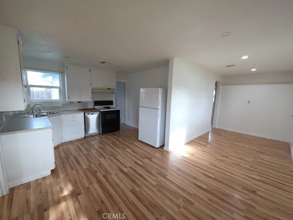a large kitchen with wooden floor and stainless steel appliances