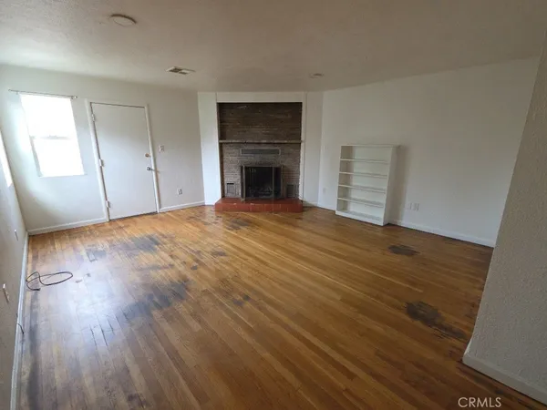 an empty room with wooden floor and fireplace