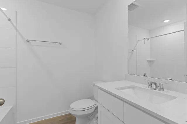 a bathroom with a granite countertop sink toilet and a mirror