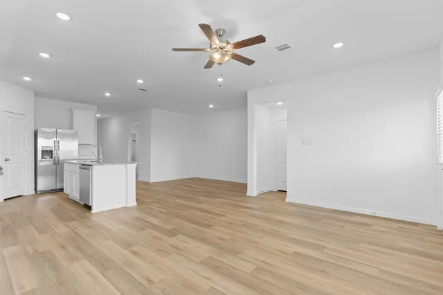 a view of an empty room with cabinet and a ceiling fan
