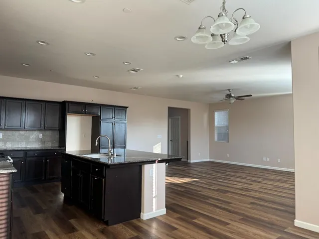 a kitchen with kitchen island granite countertop a sink cabinets and wooden floor