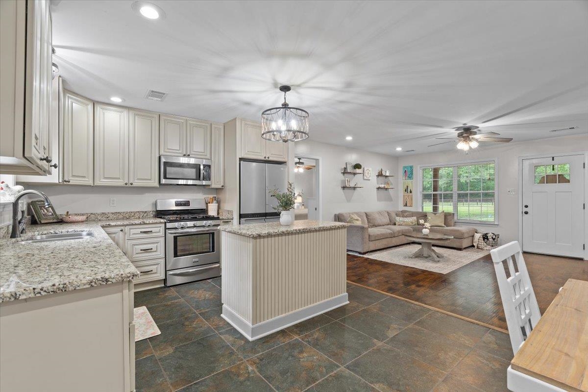 150 Liberty Road Moscow, TN 38057 - Photo 8 of 36 Open-concept kitchen and living area featuring granite countertops, stainless steel appliances, a kitchen island with beadboard paneling, recessed lighting, and slate-style flooring