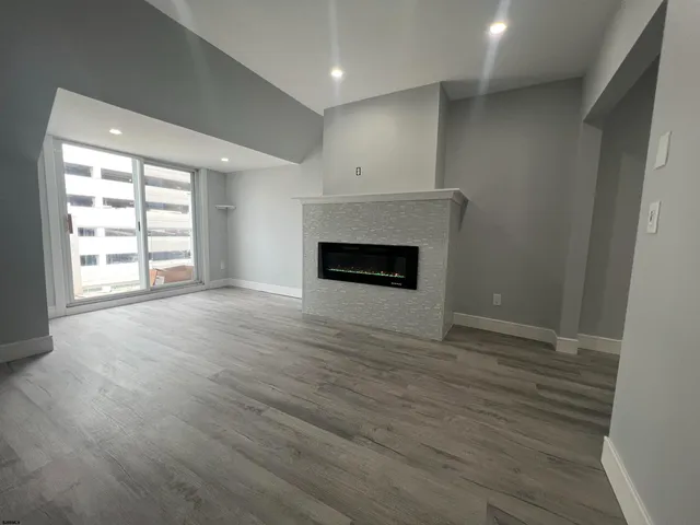 an empty room with wooden floor fireplace and windows