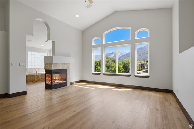 12317 Cypress Point Way Draper, UT 84020 - Photo 17 of 41 Vaulted ceiling master bedroom with wood-finish flooring, a contemporary fireplace, and expansive windows