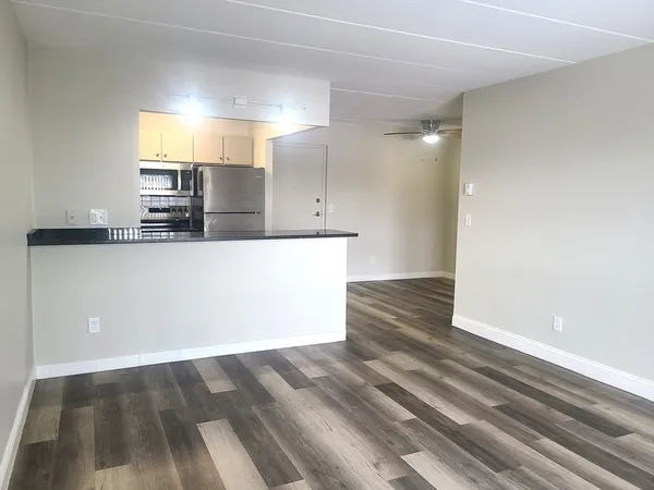 a view of a kitchen with kitchen island a sink wooden floor and a refrigerator